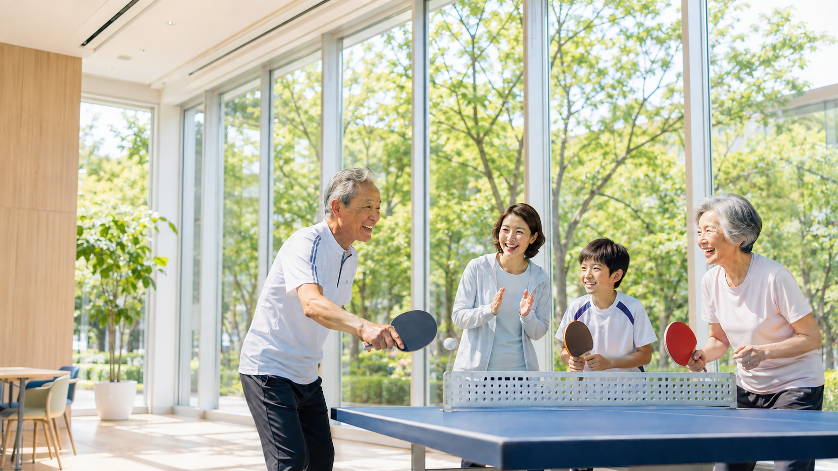 大きな窓から緑を望む明るい室内で、世代を超えて卓球を楽しむ人々